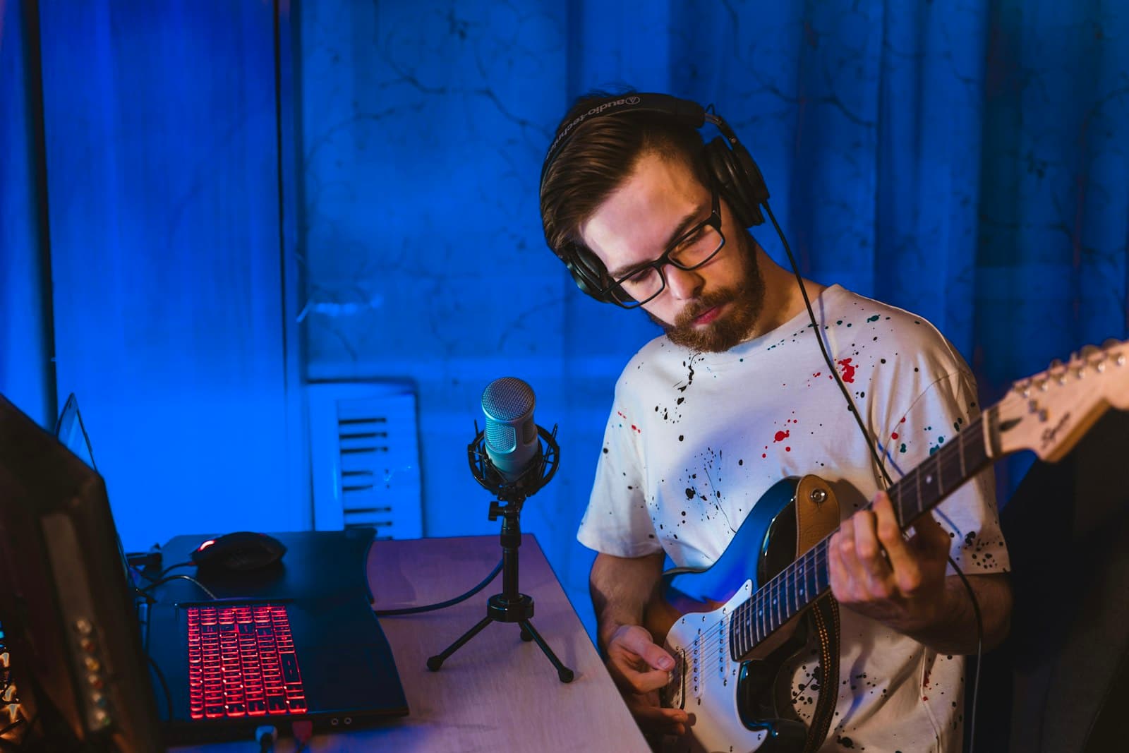 Musisi merekam gitar elektrik di studio dengan headphone