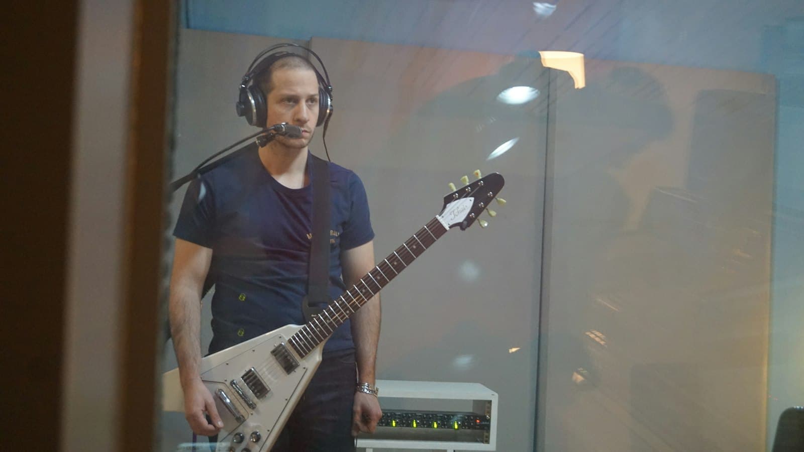 Musisi bermain gitar sambil memakai headphone